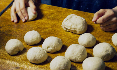 Sticker - Closeup shot of baker's hands making dough for bread on a wooden table