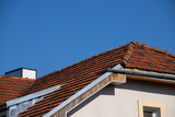 Fototapeta Konie - Ceramic tile roof with chimney and white wall, blue sky as background