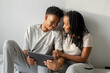 happy african couple sit on bed with tablet 