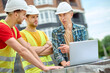 © zinkevych - Engineer and two workers discussing near laptop outdoors