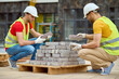 © zinkevych - Two men stacking bricks at construction site