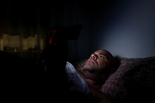 Middle-aged Caucasian Man Lying In Bed Looking At The Phone Before Sleeping.