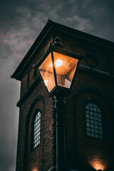 Sticker - Vertical low angle shot of an illuminated street lamp near a building