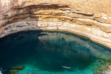 Wall Mural - Middle East, Arabian Peninsula, Oman, Muscat, Quriyat. People swimming in the Bimmah Sinkhole. (Editorial Use Only)