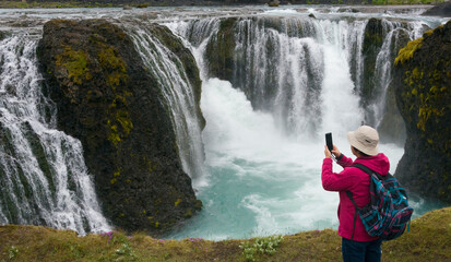 Wall Mural - Tourist photographing Sigoldu Waterfall, Iceland