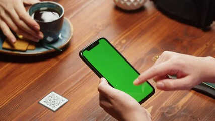 Woman using smartphone with chroma green screen, online menu in cafe. Scanning QR code in restaurant. Modern technology, ordering meal in application. Contactless touch-free payment in app.