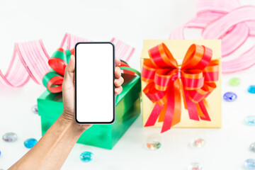 Wall Mural - Hand holding blank white screen smartphone with Christmas gift box on background