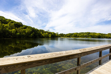 Sticker - Wooden bridge over the reflective clean lake Carver surrounded by dense trees in Minnesota