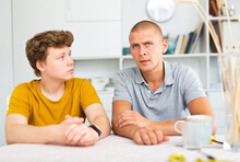 Portrait Of Teen Boy Having Conversation With Man In Home Interior