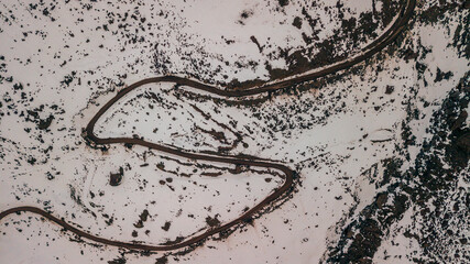 Wall Mural - Aerial view of a mountainous landscape with a pathway and peaks covered in snow