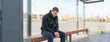 man sitting on bus stop and waiting for public transport
