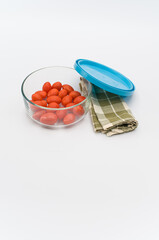 Poster - fresh organic datterini tomatoes in a glass bowl and table napkin on a white table background