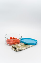 Poster - fresh organic datterini tomatoes in a glass bowl and table napkin on a white table background