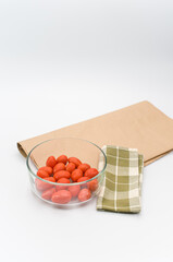 Poster - fresh organic datterini tomatoes in a glass bowl on a white table background