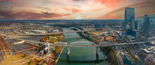 A Gorgeous Aerial Shot Of The Silky Green Waters Of The Cumberland River With Bridges Across The River And Autumn Colored Trees With A Vast View Of The Cityscape With Powerful Clouds At Sunset