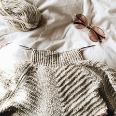 Wall Mural - Top view of a blouse, needles, and sunglasses on a white texture