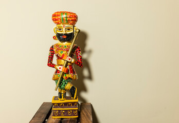 Wall Mural - Handmade colorful wooden Rajasthani Doorkeeper or guard souvenir standing with plain background.