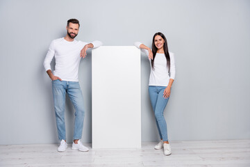 Full length body size view of attractive cheerful couple demonstrating copy space poster isolated over grey pastel color background