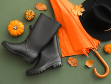 Rubber Boots, Umbrella, Hat And Pumpkins On Green Background, Closeup