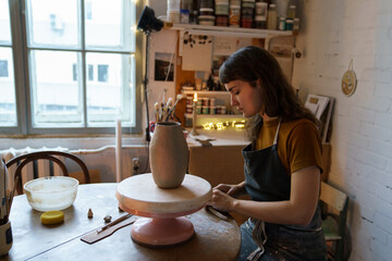 Poster - Concentrated young woman creating vase of clay during entertainment hobby classes in art studio. Creative female work with potter in workshop. Self employment small business or art therapy concept