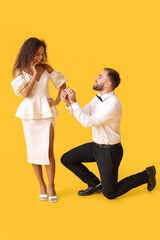 Wall Mural - Young man proposing to his girlfriend on color background