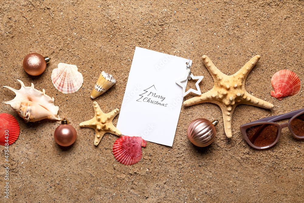 Christmas composition with greeting card on beach sand