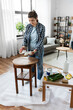 © Syda Productions - furniture restoration, diy and home improvement concept - happy smiling woman applying solvent to rag for cleaning old wooden table for renovation