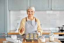 Cooking, Food And Culinary Concept - Happy Smiling Senior Woman With Cupcakes In Baking Mold Showing Thumbs Up On Kitchen At Home