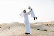 © oneinchpunch - Father and son spending time in the desert on a safari day. Arabian family from the emirates wearing the traditional white dress. Concept about lifestyle and middle eastern cultures