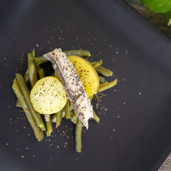 Wall Mural - Closeup shot of a dish of green beans with potatoes and tuna belly fillets on a dark plate