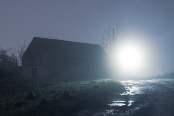 Canvas Print - An abandoned barn back lighted on a foggy winters night in the countryside.