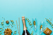 Bottle of champagne with colored glitter, confetti and gift box space for text on colorfull background, top view. Hilarious, christmas and birthday celebration