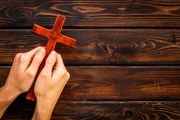 Christian wooden cross in hands. Faith and prayer concept