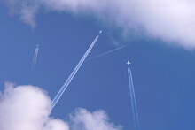 Many Distant Passenger Jet Planes Flying On High Altitude On Clear Blue Sky Leaving White Smoke Trace Of Contrail Behind. Busy Air Transportation Concept