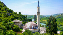 View Of The Karadoz Bey Mosque Mostar With Green Trees With A Blue Sky In Bosnia And Herzegovina