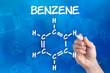 hand with pen drawing the chemical formula of benzene