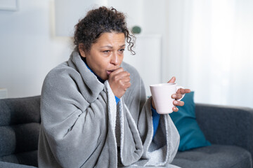portrait of black woman suffering cold and flu at home coughing