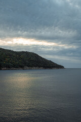 Sticker - Beautiful shot of forested sea cliffs under a blue cloudy sky during the sunset