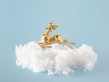 Golden Reindeer Christmas Decoration On Fluffy Cloud Against Pastel Blue Background. Happy New Year Idea, Winter Holidays. 