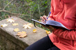 © ADDICTIVE STOCK - Unrecognizable woman writing in notebook in nature