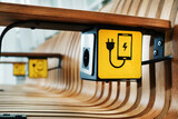 Fototapeta  - A designer wooden bench with sockets and a yellow sign for charging smartphones in the waiting room.