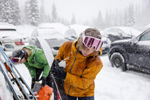 Young Woman Preparing Ski Equipment In Snowy Parking Lot