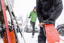 Close Up Man Preparing Skis In Snowy Parking Lot