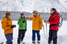 Friends Taking Break From Skiing With Coffee Below Snowy Mountain