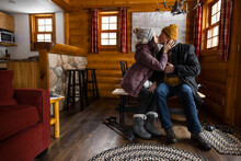 Affectionate Couple In Warm Clothing Kissing In Log Cabin