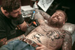 © Mr. Prof - Professional tattooist does tattoo on the skin of his client in the salon