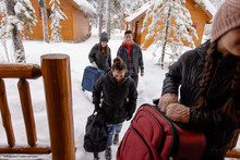 Family With Luggage Arriving At Snowy Winter Cabin