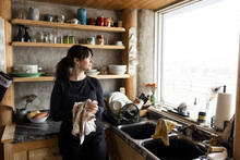 Woman Looking Out Of Window In Cabin Kitchen