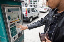 Close Up Of Man Pressing Keypad Of Ticket Machine On Sidewalk