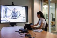 Businesswoman On Video Conference Meeting With Mentor In Room